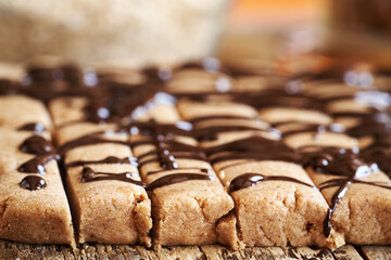 Homemade chocolate bars made of whey protein powder, ground oat flakes, maple syrup, cinnamon and nut butter, closeup