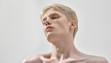 Side view of young man with blonde hair tilting head upward in confident pose. Concept of skincare,...