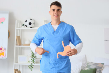 Male medical student pointing at picture of stomach at home