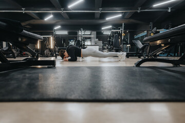 Active woman holding a plank position in a modern gym environment, focused on exercise and training. Capturing fitness lifestyle, strength development, and workout routines.