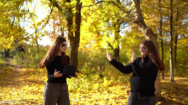      Teenage friends with stage makeup of a mime during an acting lesson celebrate Halloween in the park near the school, act out scenes and having fun