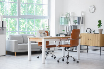 Interior of light office with workplace, sofa and water cooler