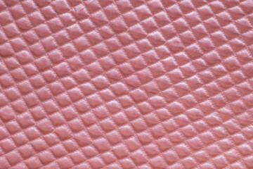 Naklejka premium Close-up of soft pink quilted fabric with a diamond pattern. Showcasing its plush texture and subtle sheen. Ideal for backgrounds or textile designs, conveying comfort and elegance.