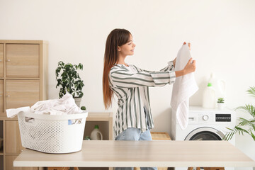 Young woman with clean towel in laundry room