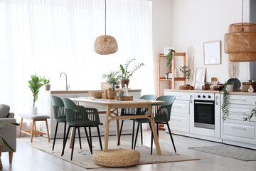 Table, chairs and wicker pouf near counter in interior of dining room