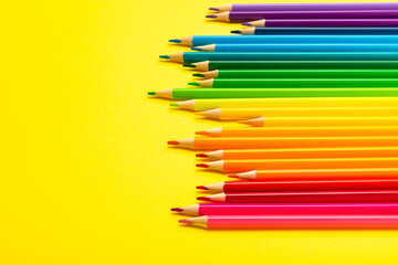 Fototapeta premium Colored pencils on a bright colored background. Equipment for coloring. Stationery for creativity.Back to school. Flatlay. Children's Creativity and Education. Rainbow.Space for text. Copy space.