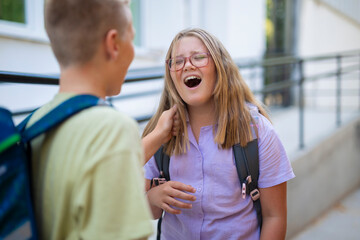 Aggressive schoolboy bullying schoolgirl by pulling her hair outside school.  
