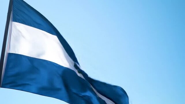 The flag of El Salvador waving in the breeze against a clear, light-blue sky