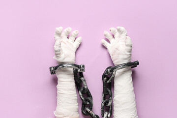 Mummy hands in chain on purple background. Halloween celebration