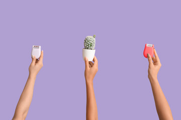 Many female hands with cactus and epilators on purple background. Depilation concept