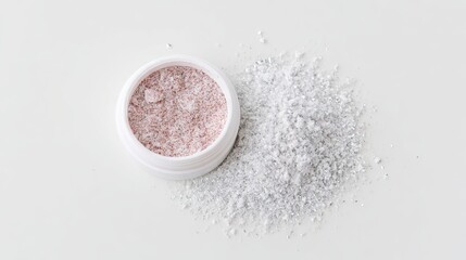 Container of shimmering cosmetic powder with pink and silver hues, scattered on a clean surface, showcasing beauty product texture and elegance for makeup enthusiasts