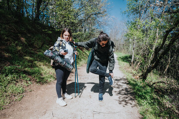 Two individuals pause on a forest trail, with trekking poles, surrounded by lush greenery, enjoying...