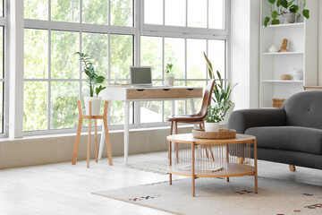 Interior of light living room with programmer's workplace and sofa