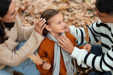 Happy family sitting in beautiful autumn park