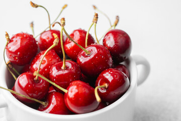 Cherries in white bowl on white background for minimal fruit snack or health food concept
