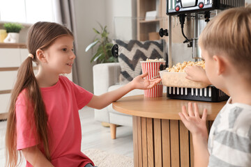 Little children with popcorn machine at home
