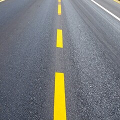 Dark gray asphalt road surface marked with distinct yellow lane dividers.