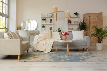 Interior of stylish living room with grey sofas, shelf units and plants