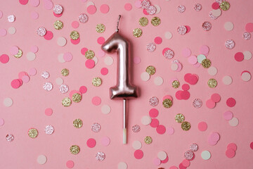 Celebration decor featuring a pink number one candle on confetti background