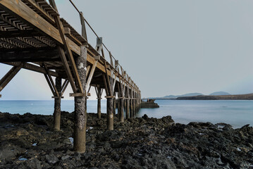 Fototapeta premium Old wooden pier stretching into the calm ocean at dusk