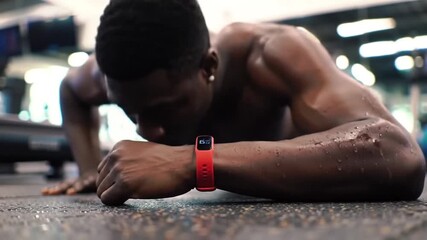 African American Man Doing Push-ups with Fitness Tracker in Gym, Intense Workout - Powered by Adobe