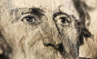 Detailed engravings of historical figures pop on close-up of US currency. Close-up reveals intricate line work and textured patterns of eyes and facial features on dollar bill.