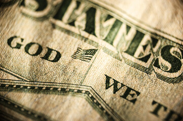 Overlapping US dollar bills showcase text IN GOD WE TRUST and UNITED STATES OF AMERICA in close-up view. Green ink and textured surfaces highlight fine details, ideal for financial or economic