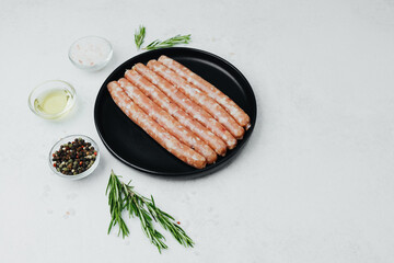 Fresh pork sausages on black plate with rosemary and salt