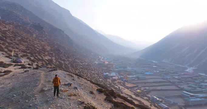 Aerial view of a tourist running toward unexplored hills near Buddhist stupa in Dingboche, Khumbu, Nepal. Ama Dablam rises in the backdrop with morning sunrays over Everest region village landscape