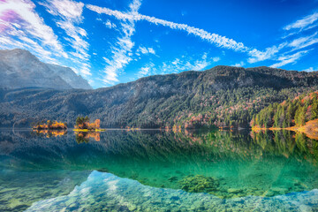 Stunning autumn landscape of Eibsee Lake in front of Zugspitze summit under sunlight.