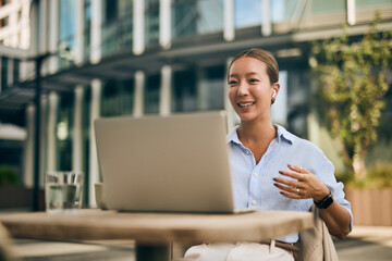 Asian Business Woman Having a Virtual Meeting Outdoors at a Modern Cafe