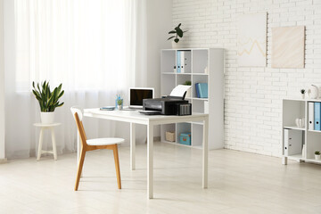 Stylish workplace with modern printer and laptop in light home office