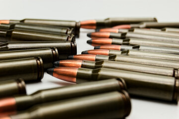 Rifle ammunition neatly lined in rows on white background, metallic casings gleam in green, brown,...