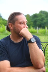 A man contemplating outdoors with a thoughtful expression on his face