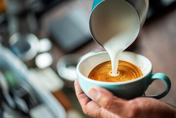 Barista Training Practice Pouring Milk for Latte Art in Workshop Setting, Showing Focused Hand...