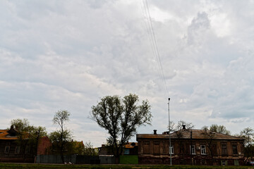 A two-story building with boarded-up windows stands in a rural setting under an overcast sky with...
