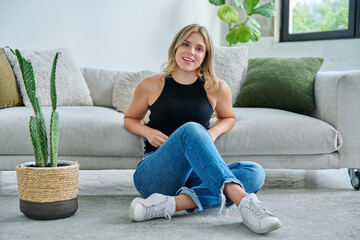 Portrait of relaxed beautiful young woman sitting at home on floor