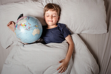 Boy sleeping in bed with globe, dreaming of travel, adventure, exploring new countries and cultures, symbolizing wanderlust, future journeys, and the dream of discovering the world.
