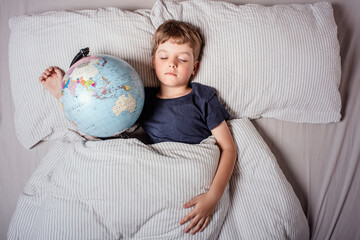 Boy sleeping in bed with globe, dreaming of travel, adventure, exploring new countries and cultures, symbolizing wanderlust, future journeys, and the dream of discovering the world.

