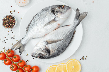 Raw dorado fish with tomatoes lemon and spices on white background