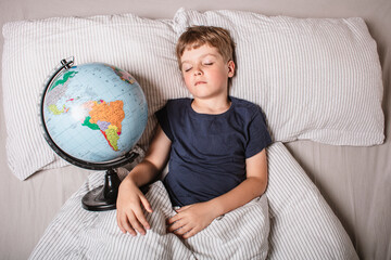 A young boy peacefully sleeping in bed while holding a globe, symbolizing childhood dreams, travel, geography, education, global unity, future exploration, and connection with the world.
