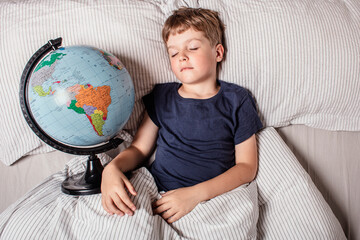A young boy peacefully sleeping in bed while holding a globe, symbolizing childhood dreams, travel, geography, education, global unity, future exploration, and connection with the world.
