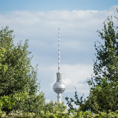Berlin TV Tower framed by green trees, summer sky, Germany