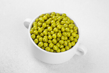 Green peas in white bowl  on bright background for clean eating, vegan food or healthy side dish concept