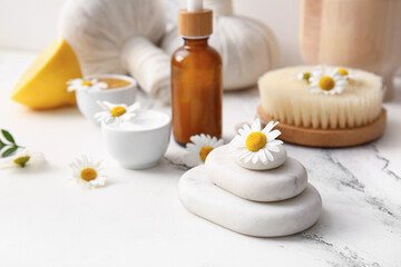 Composition with chamomile flowers and spa stones on marble background, closeup
