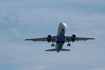 Airplane in the cloudy sky. The plane gaining altitude after takeoff from the airport.