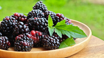 Sweet blackberries on a wooden plate on the table