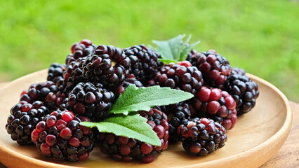 Sweet blackberries on a wooden plate on the table