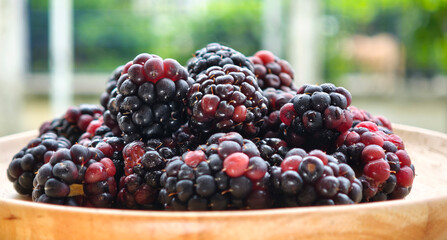 Sweet blackberries on a wooden plate on the table