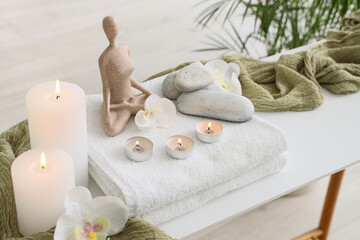 Composition with spa accessories, burning candles and decorative figurine on table in salon